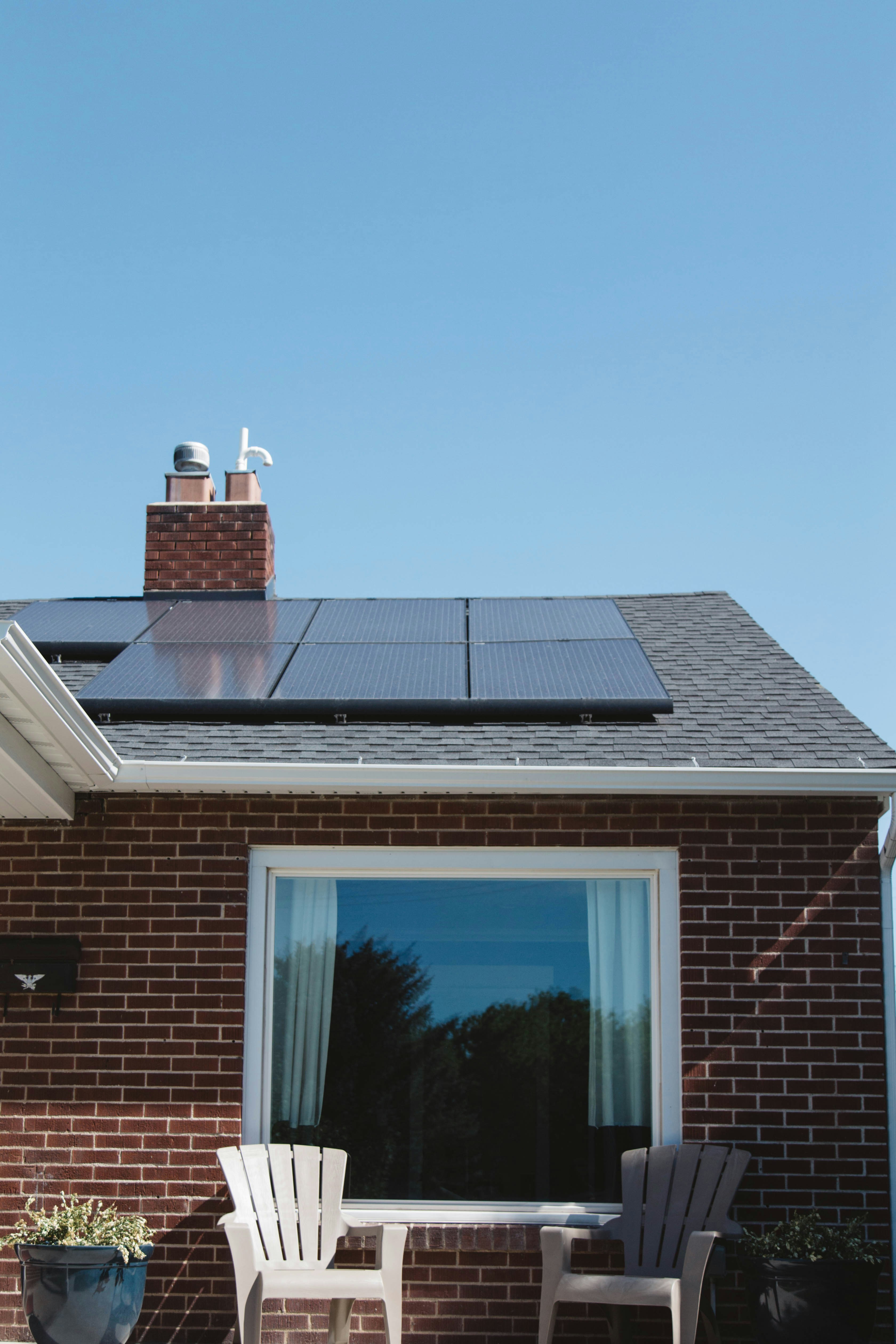 Home with rooftop solar panels and landscaped garden on a sunny day